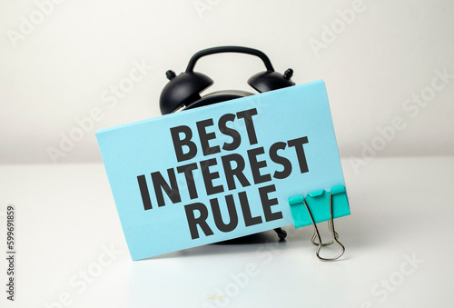 best interest rule is written in a blue sticker near a black alarm clock