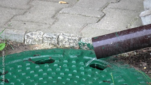 Regenwasser läuft aus einer Regenrinne in ein Gullideckel