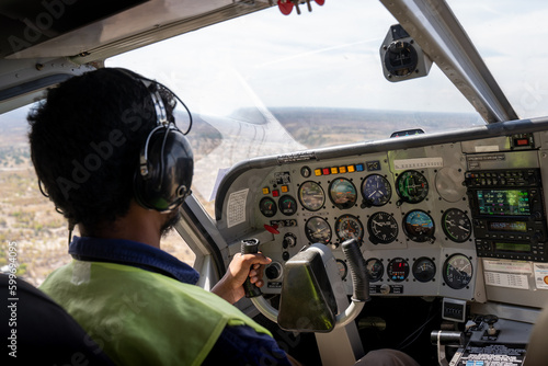 Pilot in Warnweste beherrscht die Cockpitinstrumente einer Gippsland GA-8 Airvan Propellerflugzeug / Kleinflugzeug über Botswana, Afrika photo