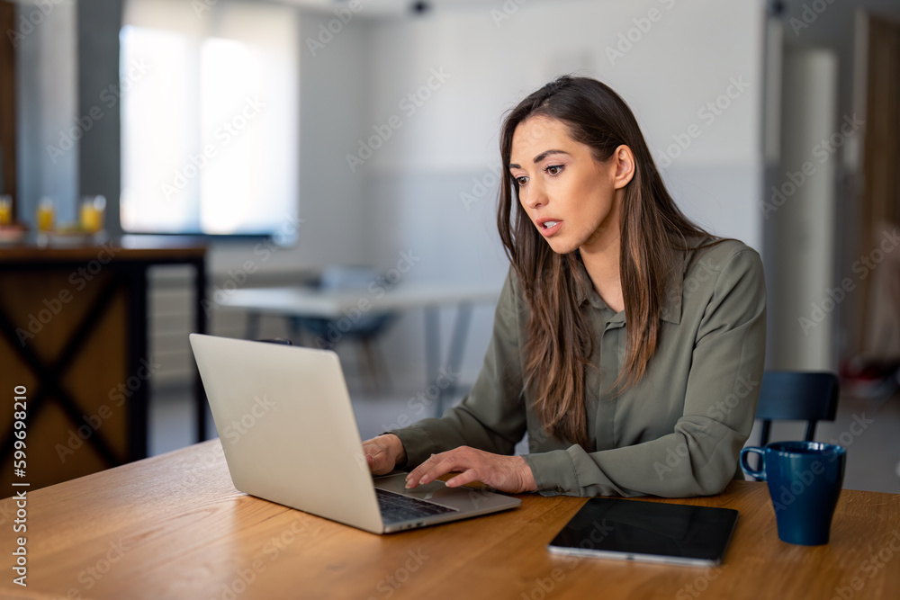 Young focused businesswoman using modern technology portable devices, typing on laptop, writing e-mails, working from home. Home office concept. Young focused businesswoman using modern technology portable devices, typing on laptop, writing e-mails, working from home. Home office concept.