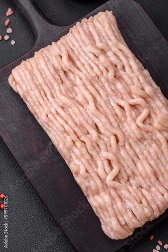 Fresh minced chicken with salt, spices and herbs on a wooden cutting board