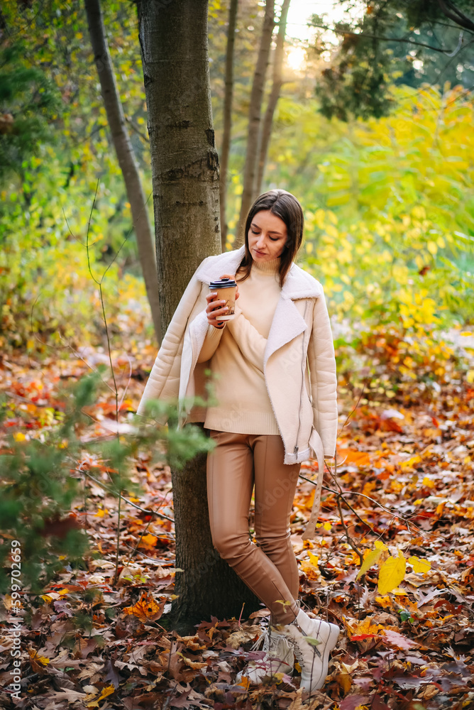 Lady in autumn park with coffee cup. Relaxed woman smelling coffee. Lady in autumn park with coffee cup. Relaxed woman smelling coffee.