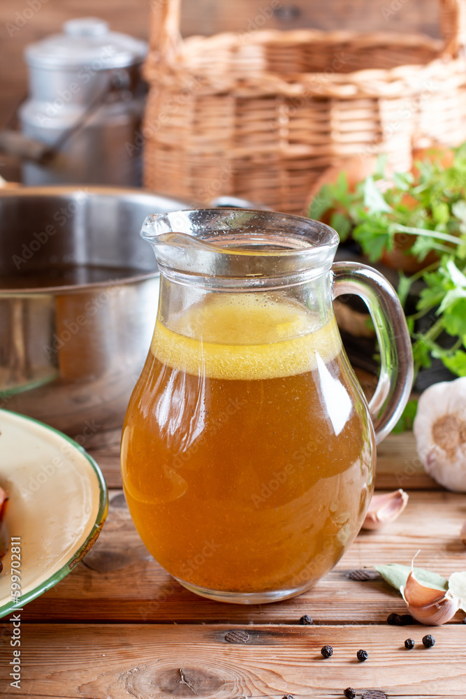 Glass jar with yellow fresh bone broth o on wooden table. Healthy low-calories food is rich in vitamins, collagen and anti-inflammatory amino acids Glass jar with yellow fresh bone broth o on wooden table. Healthy low-calories food is rich in vitamins, collagen and anti-inflammatory amino acids