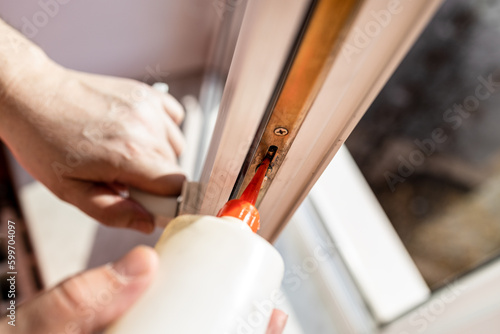 Fotografie lubricating of open window frame close up at home on sunny day
