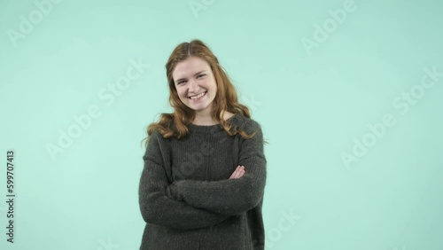 This portrait depicts an emotional girl making gestures. She is a funny Caucasian girl wearing a sweater and laughing while looking at the camera