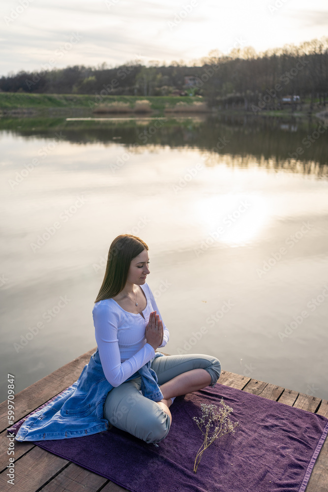 Woman relaxingly practicing meditation in nature by the lake. Nature background. Spiritual and emotional concept. Woman relaxingly practicing meditation in nature by the lake. Nature background. Spiritual and emotional concept.
