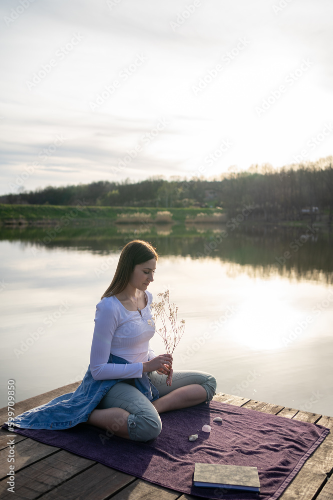 Woman relaxing on lakeshore, nature concept, sunset.