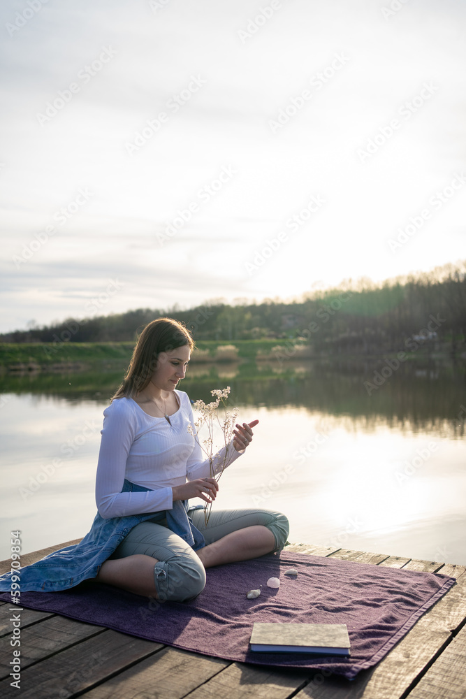 Woman relaxing on lakeshore, nature concept, sunset.