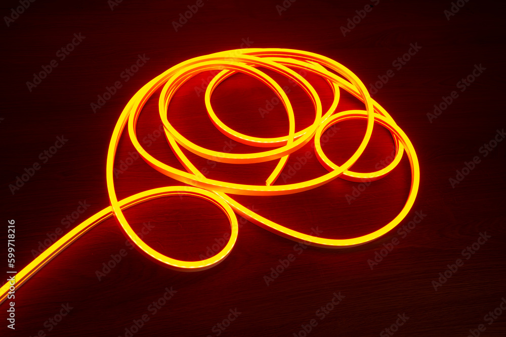 Flexible neon is lying on the table. Neon orange light for the production of outdoor advertising.Light strip for illumination. Flexible neon is lying on the table. Neon orange light for the production of outdoor advertising.Light strip for illumination.