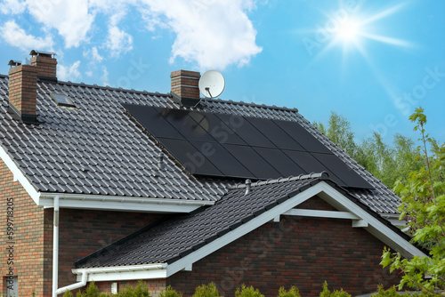 Foto Modern house, dark solar panels, sunlit sky