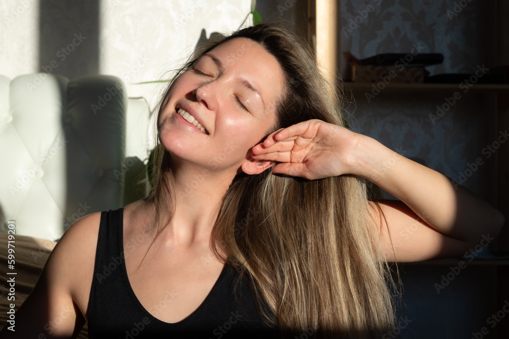 Fototapeta premium Young pretty woman with closed eyes touching her perfect skin and hair. Beautiful portrait 30s aged woman. Daily female care routine concept