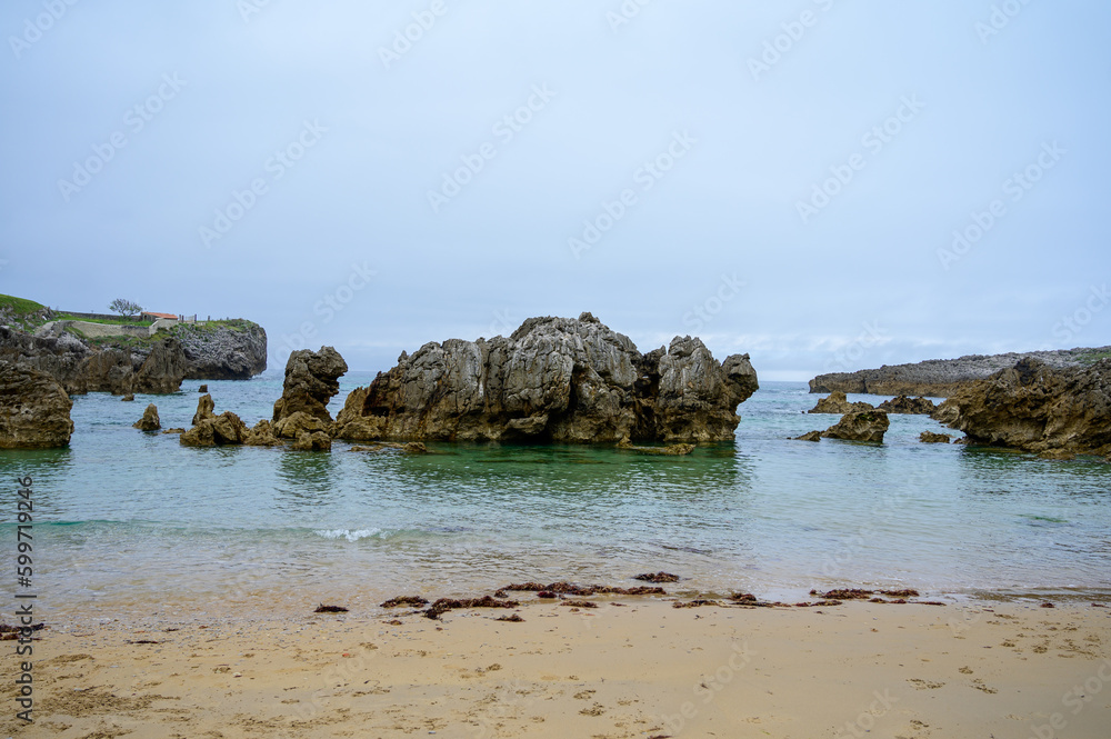 View on Playa de Toro in Llanes, Green coast of Asturias, North Spain with sandy beaches, cliffs, hidden caves, green fields and mountains.