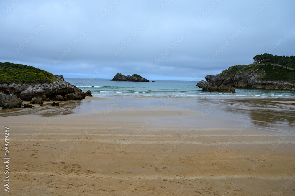 View on Playa de Palombina Las Camaras in Celorio, Green coast of Asturias, North Spain with sandy beaches, cliffs, hidden caves, green fields and mountains.