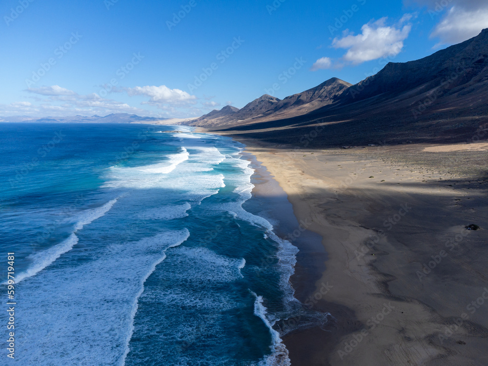 Aerial view on difficult to access golden sandy Cofete beach hidden behind mountain range on Fuerteventura, Canary islands, Spain