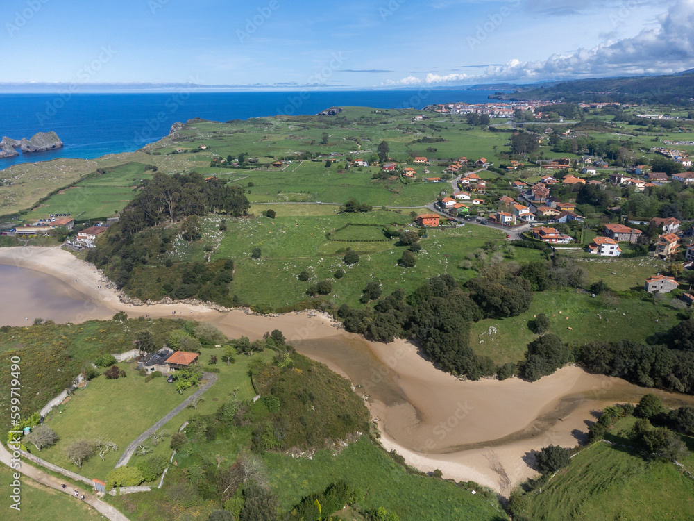 Aerial view on Playa de Poo during low tide near Llanes, Green coast of Asturias, North Spain with sandy beaches, cliffs, hidden caves, green fields and mountains.