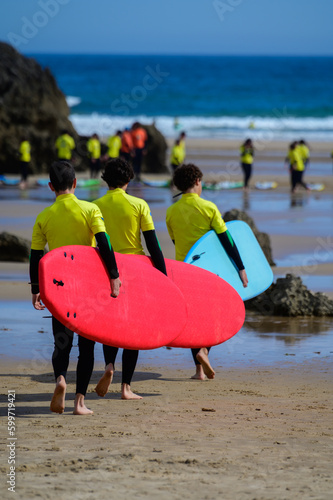 Young surfers train on Playa de Palombina Las Camaras in Celorio, Green coast of Asturias, North Spain with sandy beaches, cliffs, hidden caves, green fields and mountains photo