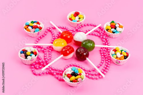 a front view colorful candies along with lollipops isolated on the pink background sweet sugar color
