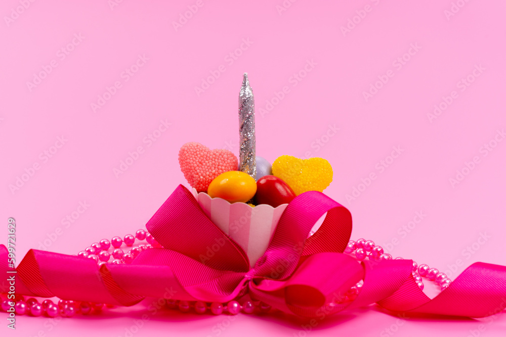 a front view little present with candies and silver candle designed with pink bow isolated on the pink desk present birthday celebration a front view little present with candies and silver candle designed with pink bow isolated on the pink desk present birthday celebration