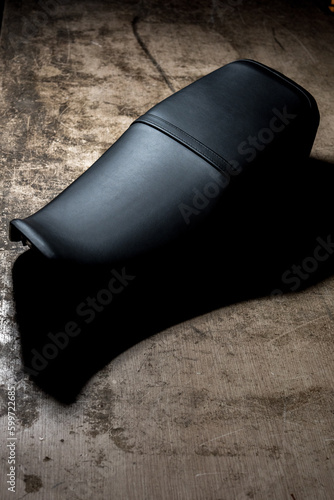 Sella sellino di una motocicletta in pelle nera su un tavolo di legno di un tappezziere, prodotto nuovo appena confezionato