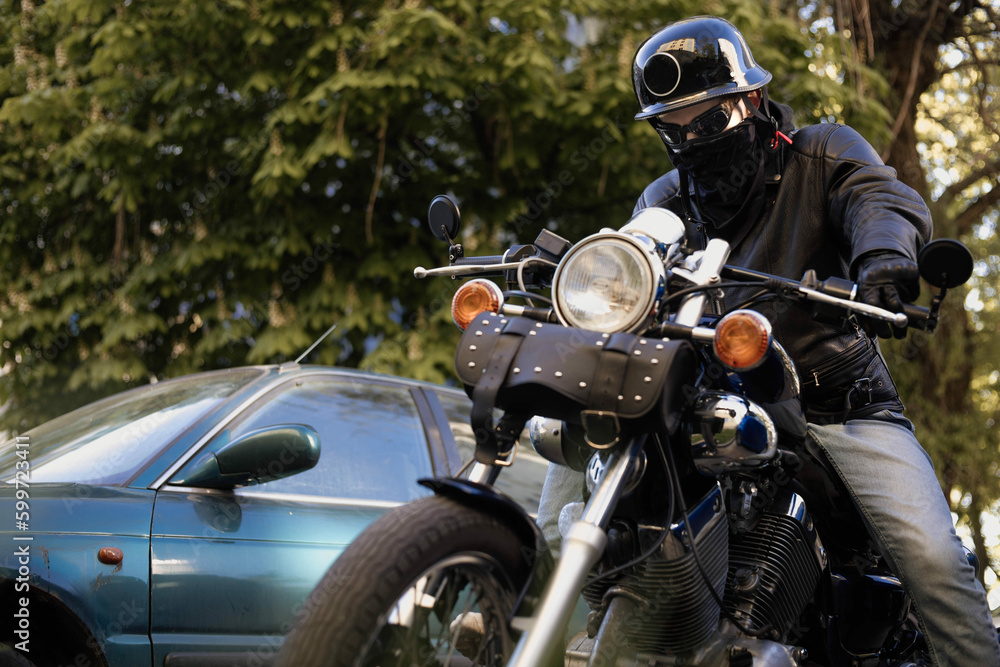 Fototapeta premium Biker in a helmet and glasses on a chopper motorcycle with a wardrobe trunk