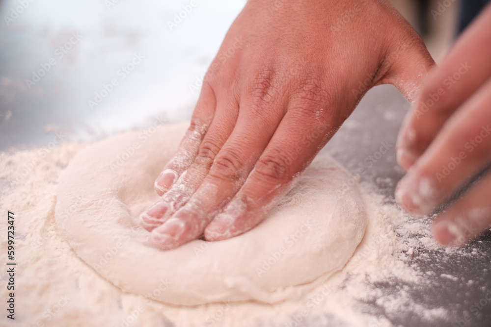 Mani di un fornaio che impastano la pasta del pane con luce naturale su un tavolo di marmo bianco - obrazy, fototapety, plakaty 