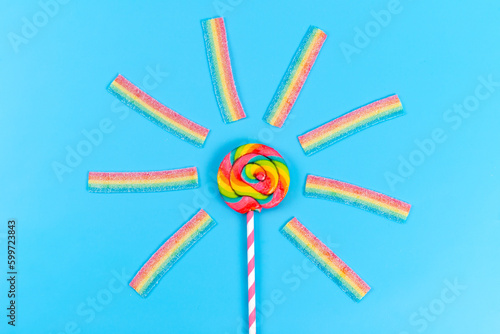 a top view colored lollipop along with chewing marmalades on the blue background rainbow sugar sweet confectionery