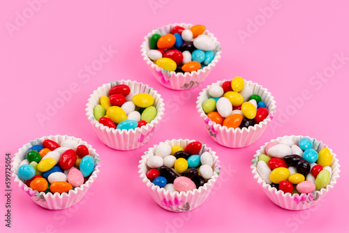 a top view colorful candies inside paper packages on the pink background sweet sugar color