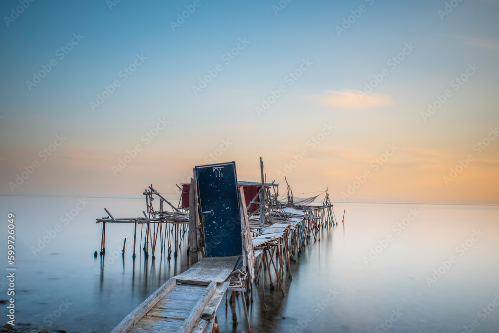 wooden piers built into the sea and helping fishing, and the sunset colors and light