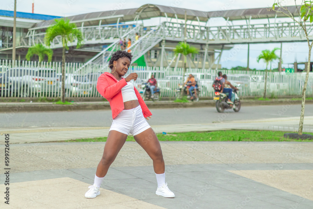 Fototapeta premium Joven Afro baila al estilo urbano en el centro de la ciudad