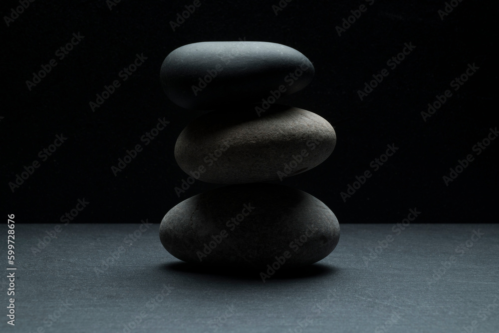 gray zen stones on a dark gray background with shadows for a podium background.a group of oval stones for product presentation gray zen stones on a dark gray background with shadows for a podium background.a group of oval stones for product presentation