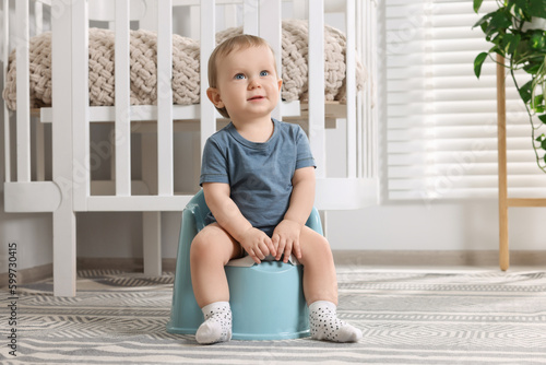Tableau sur toile Little child sitting on plastic baby potty indoors