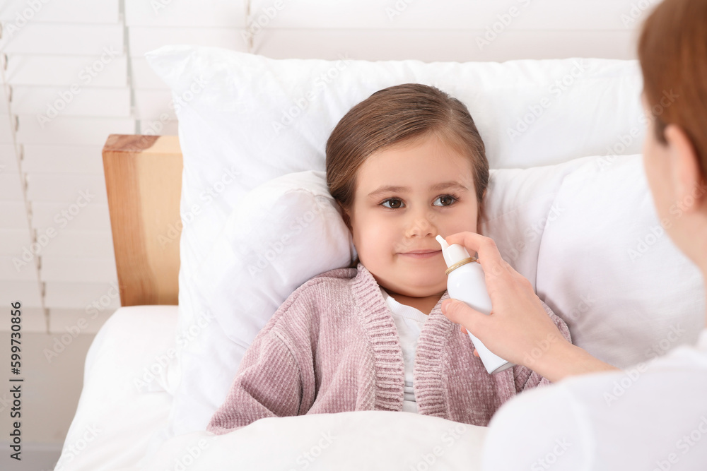Mother using nasal spray to treat her little daughter on bed Mother using nasal spray to treat her little daughter on bed