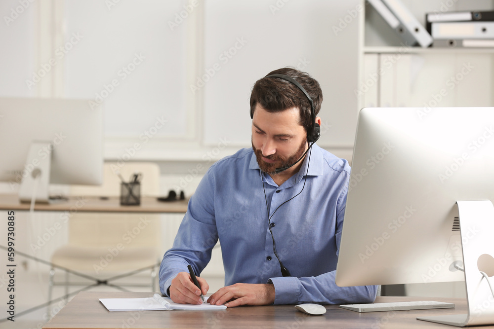 Fototapeta premium Hotline operator with headset working in office, space for text