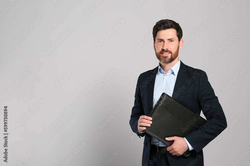 Handsome real estate agent with documents on grey background, space for text Handsome real estate agent with documents on grey background, space for text