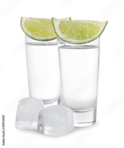 Shot glasses of vodka with lime slices and ice on white background