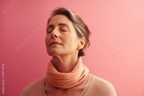 Portrait of a middle-aged woman with closed eyes on a pink background