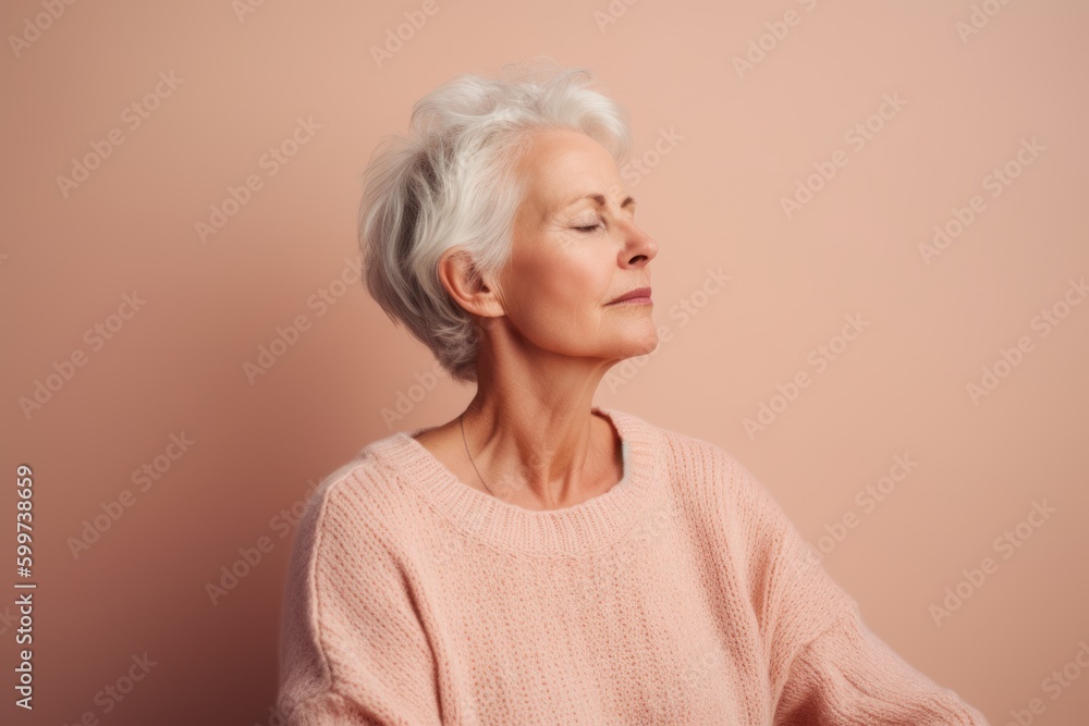 Portrait of a senior woman in a pink sweater on a pink background