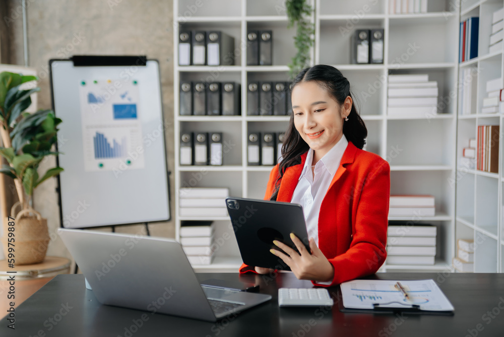 Beautiful Asian business woman typing laptop and tablet Placed at the table at home office Beautiful Asian business woman typing laptop and tablet Placed at the table at home office