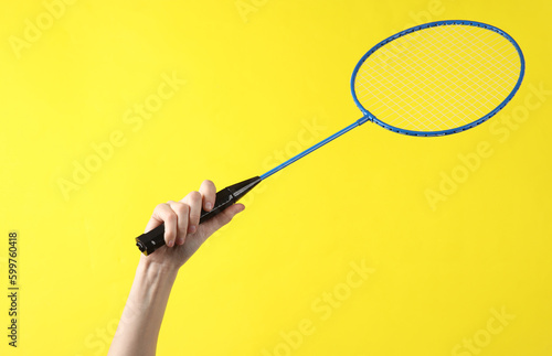 Hand holding batbinton racket on yellow background © splitov27