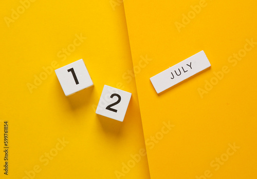 White calendar cubes with date july 12 on yellow background. Creative layout