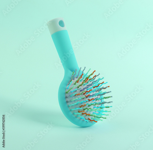 Colored hairbrush levitating on blue background with shadow. Minimal beauty still life