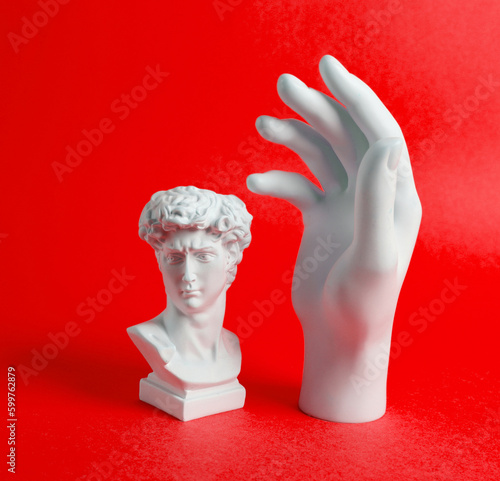 Antique David bust with statue hand on red background. Minimal still life photo