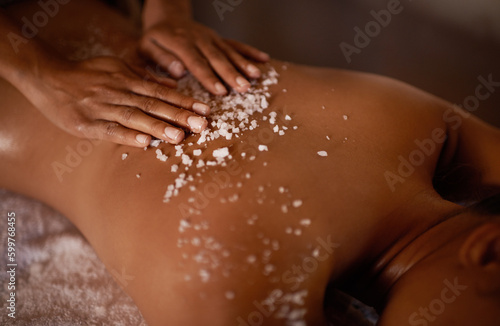 Salt, spa scrub and beauty therapist hands with woman customer at a hotel with massage. Exfoliate therapy, luxury and relax treatment of a female person back for skincare and wellness exfoliation photo