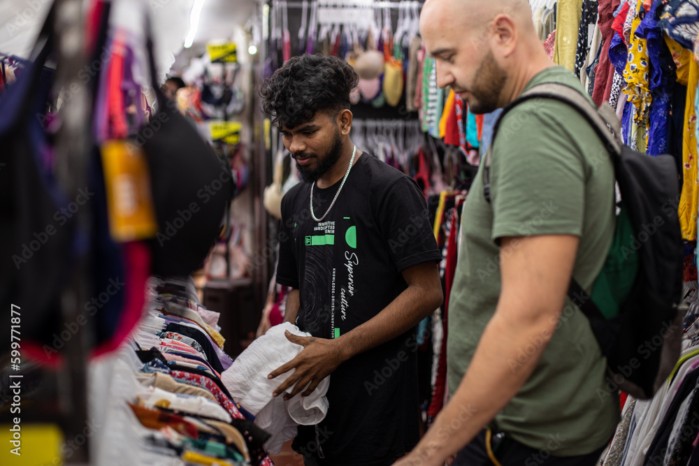Portrait of bearded people taking and selecting apparel inside shopping center . Discount and sales. 