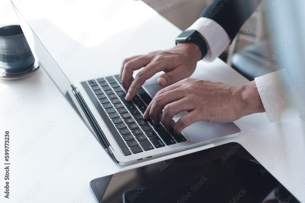 Businessman working on laptop computer on white table at office. Business man hands typing on laptop, online working, surfing the internet, close up Businessman working on laptop computer on white table at office. Business man hands typing on laptop, online working, surfing the internet, close up