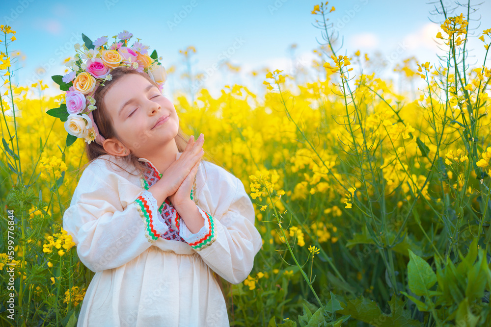 Dreaming Beautiful young girl with flower chaplet, ethnic folklore dress with traditional Bulgarian embroidery during sunset on a rapseed agricultural field Dreaming Beautiful young girl with flower chaplet, ethnic folklore dress with traditional Bulgarian embroidery during sunset on a rapseed agricultural field