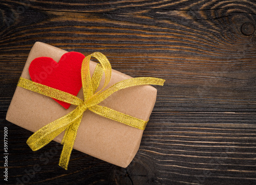gift box with Golden ribbon and red heart on wooden texture dark background, top view, symbol, Valentine's day