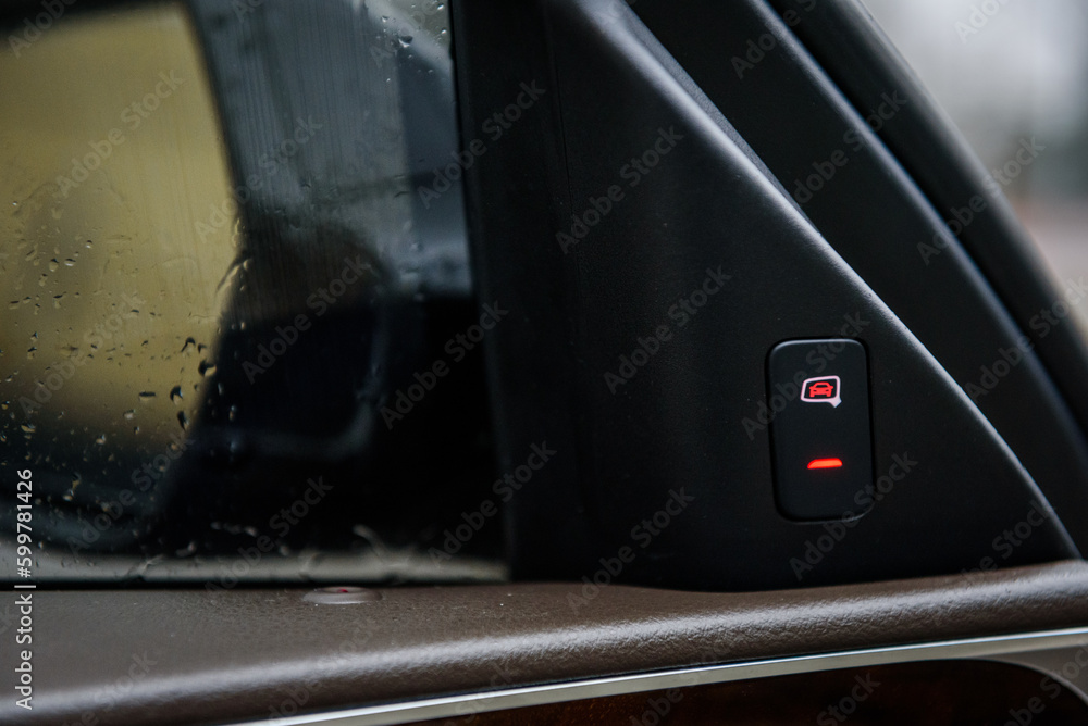 View from the middle on left front mirror from the driver. Button for turning on and off the blind spot sensor. Activate the blind spot sensor. Closeup details. View from the middle on left front mirror from the driver. Button for turning on and off the blind spot sensor. Activate the blind spot sensor. Closeup details.