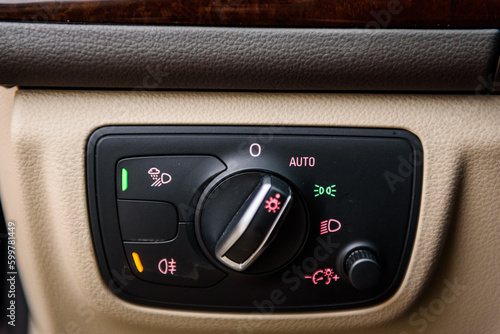 Headlights control unit with buttons for controlling headlights, fog lamps, parking lights and dimming the dashboard in a new modern premium luxury car. Details closeup. © Serhii