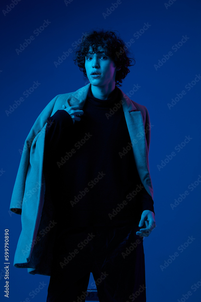Man fashion in jacket poses against dark blue background, neon light, style and trends, mixed light, men's fashion, copy place Man fashion in jacket poses against dark blue background, neon light, style and trends, mixed light, men's fashion, copy place